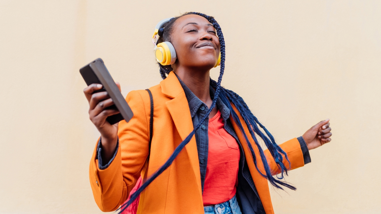 Person wearing headphones, listening to music on their smartphone.