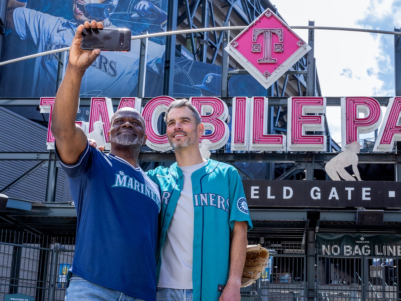 ​​Two men take a selfie while standing outside of T-Mobile Park.​ 