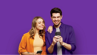 Un hombre y una mujer mirando su teléfono y sonriendo.